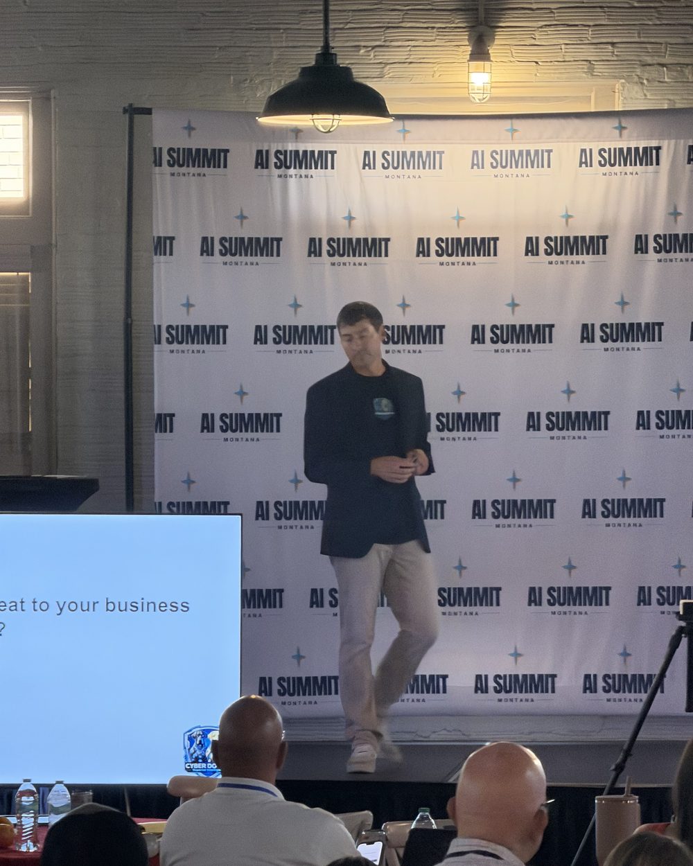 A speaker presenting on stage in front of the AI Summit backdrop